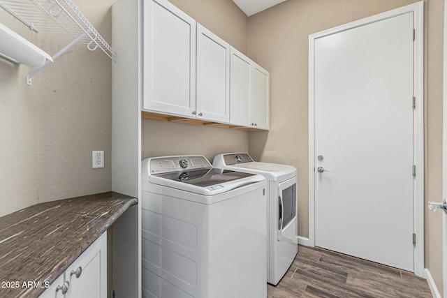 clothes washing area featuring dark wood-type flooring, cabinets, and washer and clothes dryer