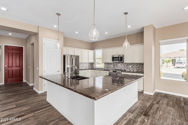 kitchen featuring sink, white cabinetry, decorative light fixtures, appliances with stainless steel finishes, and backsplash