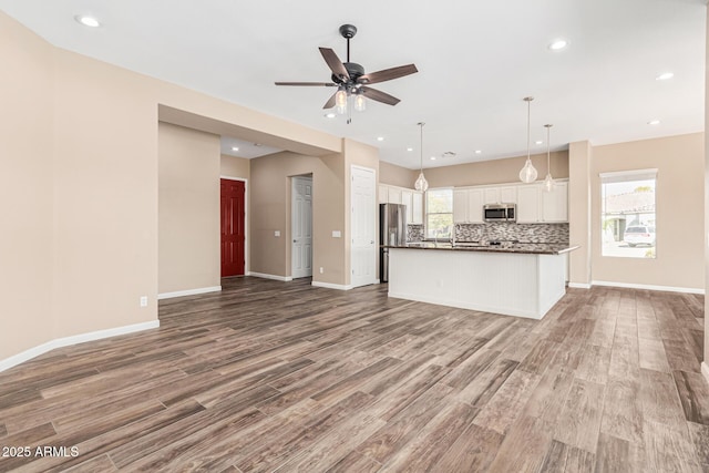 kitchen with a kitchen island, tasteful backsplash, white cabinetry, hanging light fixtures, and stainless steel appliances