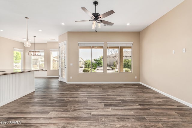 unfurnished living room featuring dark wood-type flooring and ceiling fan with notable chandelier