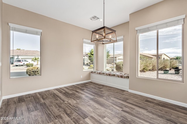 unfurnished dining area featuring an inviting chandelier and wood-type flooring