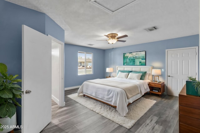 bedroom with dark wood-type flooring, a textured ceiling, and ceiling fan