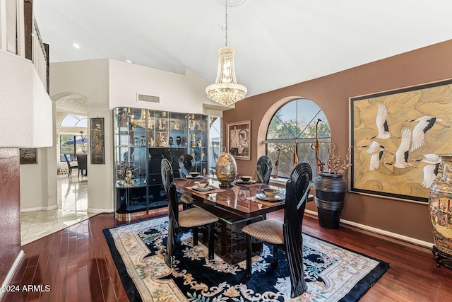 dining area featuring dark hardwood / wood-style floors, a healthy amount of sunlight, lofted ceiling, and a chandelier