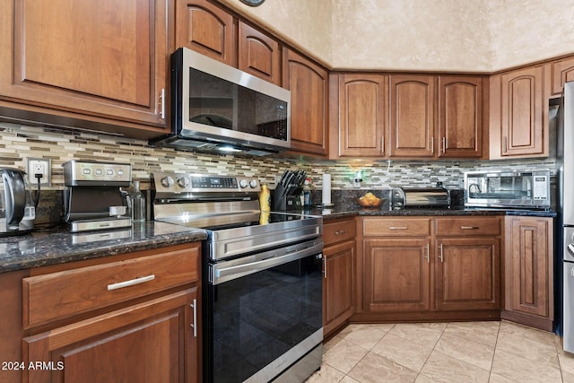 kitchen with decorative backsplash, light tile patterned floors, appliances with stainless steel finishes, and dark stone counters