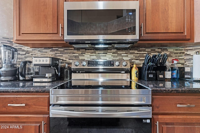 kitchen featuring appliances with stainless steel finishes, backsplash, and dark stone countertops