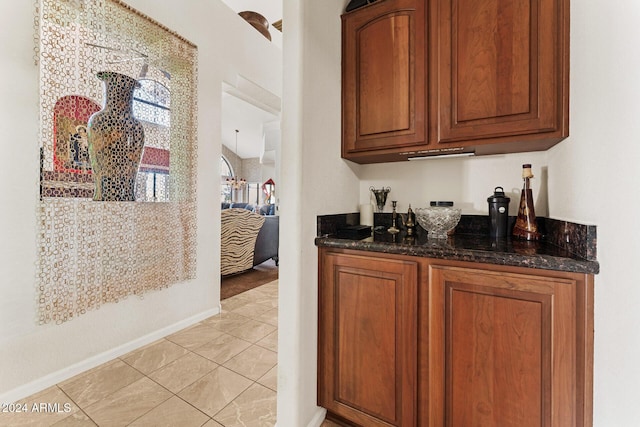 bar featuring light tile patterned flooring and dark stone countertops