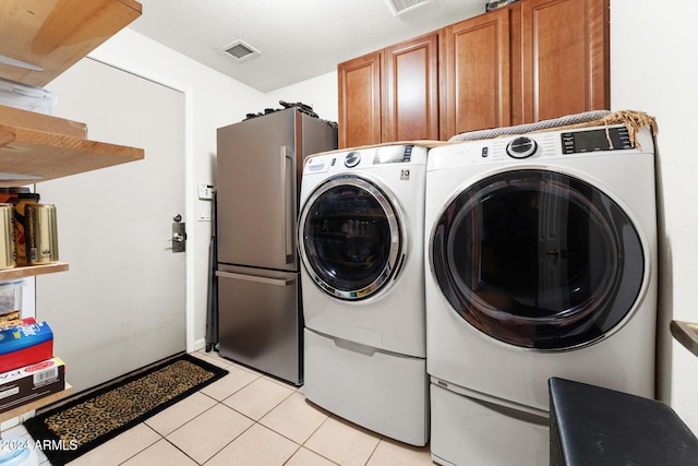 laundry area featuring washer and dryer, light tile patterned flooring, and cabinets