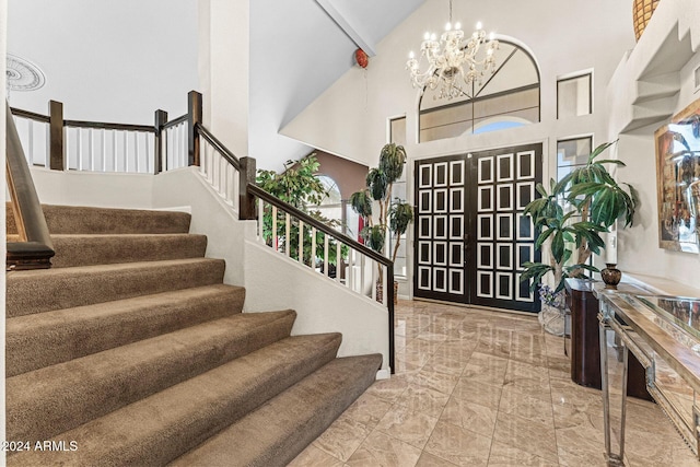 entryway with beamed ceiling, a towering ceiling, and a notable chandelier