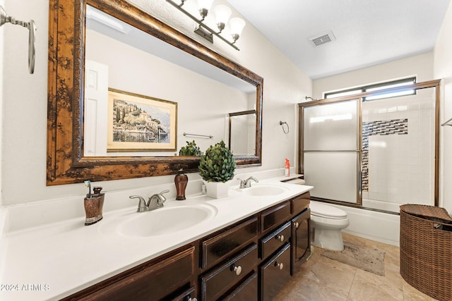 full bathroom featuring vanity, toilet, and shower / bath combination with glass door