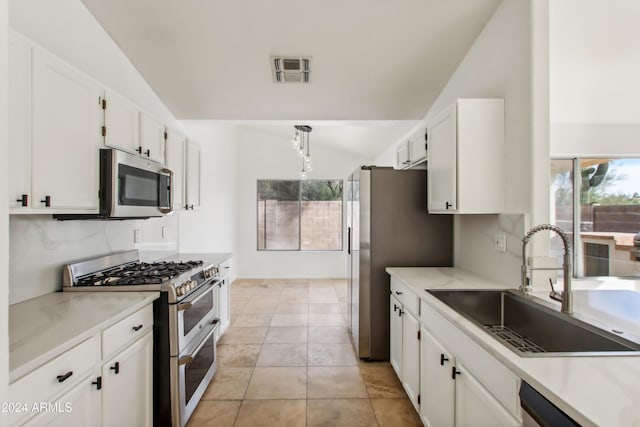 kitchen featuring visible vents, lofted ceiling, a sink, white cabinets, and appliances with stainless steel finishes