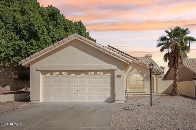 view of front facade featuring stucco siding, concrete driveway, an attached garage, and a tile roof