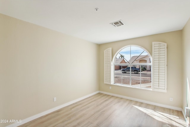 unfurnished room featuring visible vents, baseboards, and wood finished floors