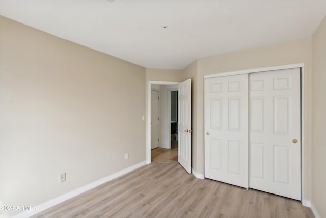 unfurnished bedroom featuring light wood-type flooring, baseboards, and a closet