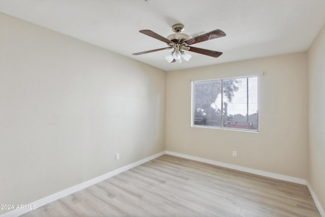 spare room with baseboards, light wood finished floors, and ceiling fan