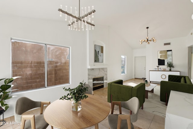 dining space with visible vents, high vaulted ceiling, an inviting chandelier, a fireplace, and light tile patterned floors