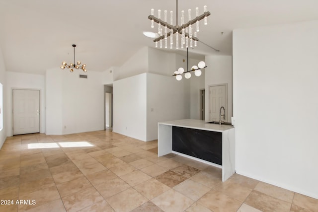 kitchen with a sink, high vaulted ceiling, pendant lighting, and a chandelier