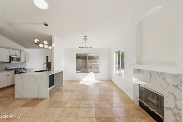 kitchen with decorative light fixtures, a high end fireplace, appliances with stainless steel finishes, white cabinets, and lofted ceiling