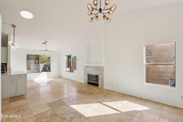 unfurnished living room with a chandelier, light tile patterned floors, high vaulted ceiling, and a premium fireplace