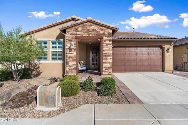 view of front of home with stucco siding, a garage, stone siding, driveway, and a tiled roof