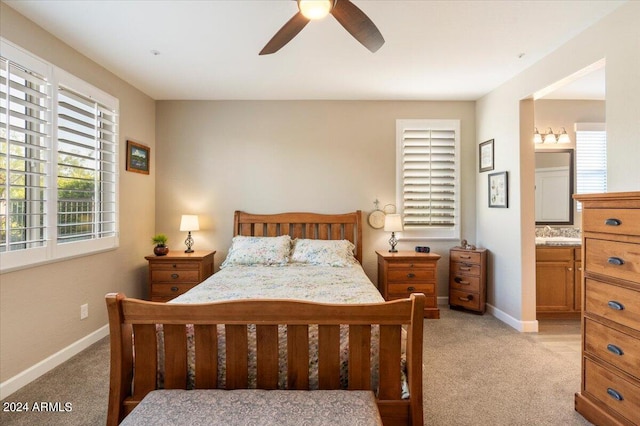 bedroom with light carpet, ensuite bath, baseboards, and ceiling fan