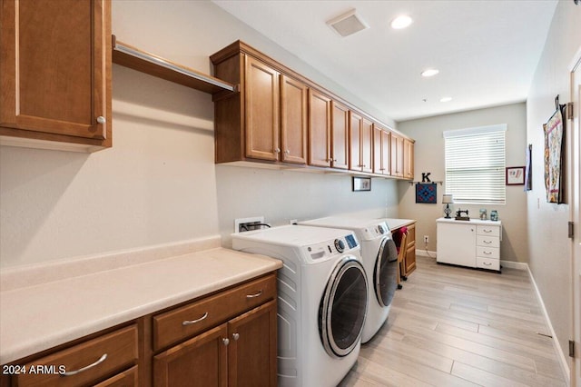 washroom with light wood-type flooring, separate washer and dryer, and cabinets