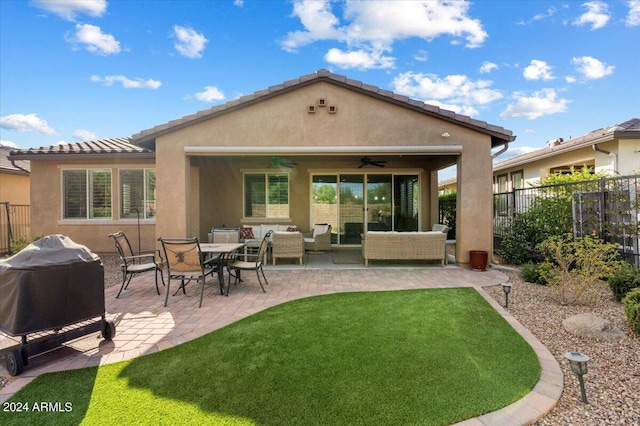 rear view of property with a lawn, an outdoor living space, ceiling fan, and a patio area