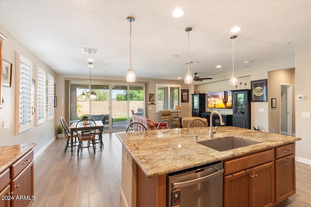 kitchen featuring light wood-type flooring, ceiling fan, a center island with sink, stainless steel dishwasher, and sink