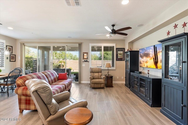 living room with ceiling fan, light wood-type flooring, and plenty of natural light