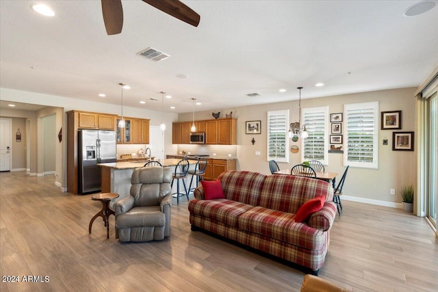 living area with light wood-style floors, recessed lighting, visible vents, and baseboards