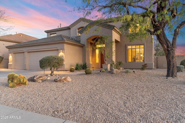 view of front of property with a garage, driveway, fence, and stucco siding