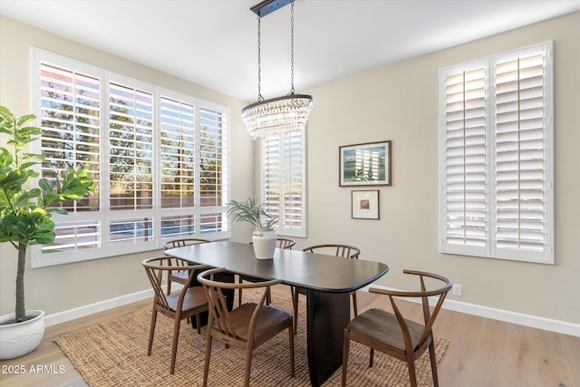 dining space featuring an inviting chandelier, baseboards, and wood finished floors