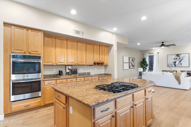 kitchen with stainless steel appliances, visible vents, a kitchen island, and light wood finished floors