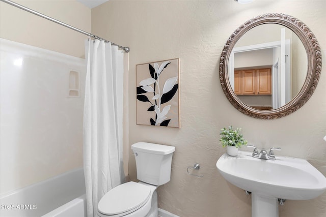 bathroom with a textured wall, shower / bath combo, a sink, and toilet