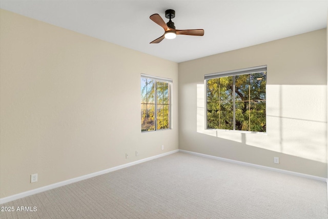 carpeted empty room featuring ceiling fan and baseboards