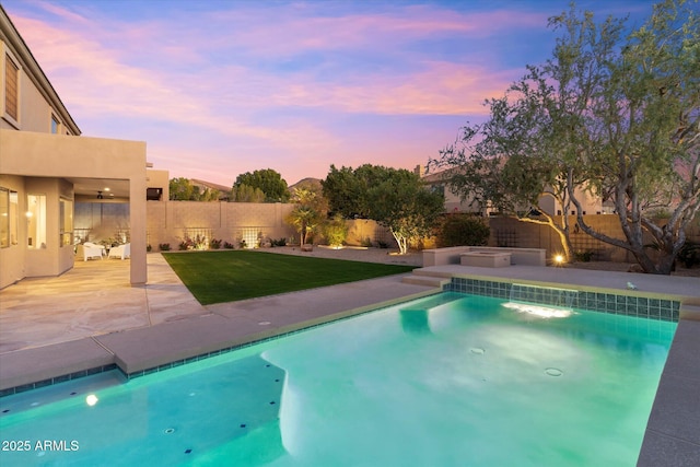 pool at dusk featuring a yard, a patio area, a fenced backyard, and a fenced in pool