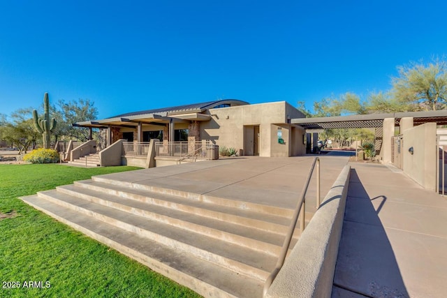 pueblo-style home featuring a front lawn, an attached carport, concrete driveway, and stucco siding