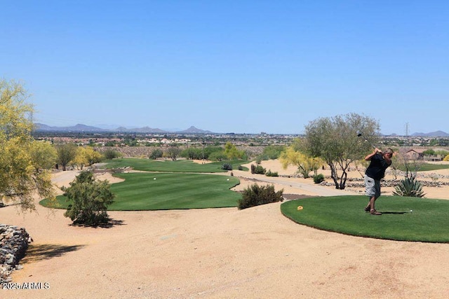 surrounding community with a mountain view, golf course view, and a lawn