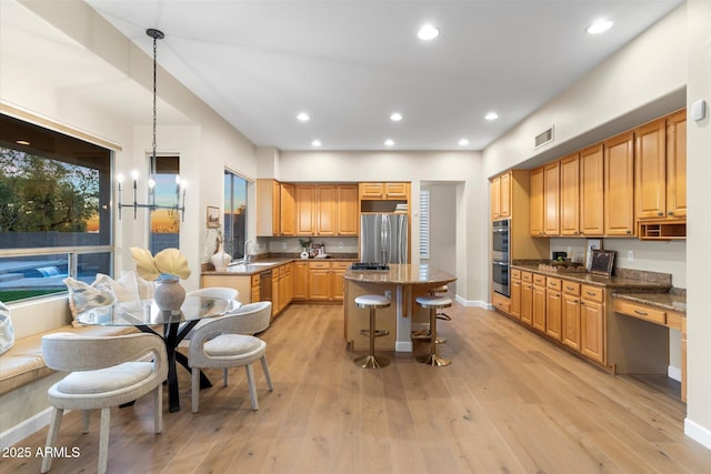 kitchen featuring light wood-style flooring, a kitchen island, a kitchen breakfast bar, stainless steel appliances, and a sink