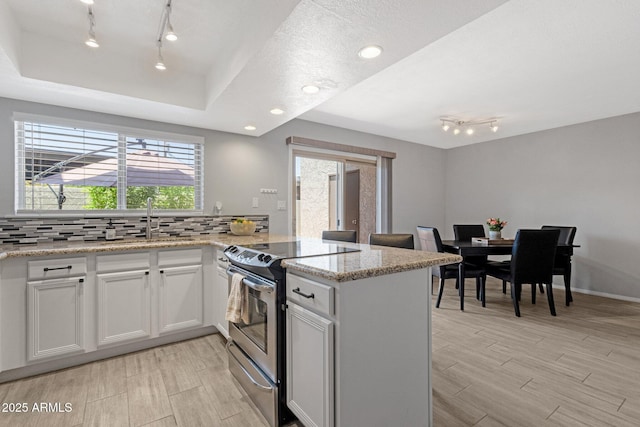 4918 N 74th St, Scottsdale, AZ 85251 - kitchen with electric stove, a peninsula, track lighting, tasteful backsplash, and light wood-style flooring
