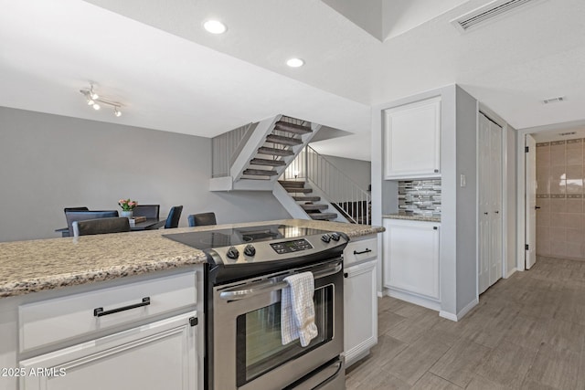 4918 N 74th St, Scottsdale, AZ 85251 - kitchen with stainless steel electric stove, white cabinetry, light stone countertops, recessed lighting, and decorative backsplash