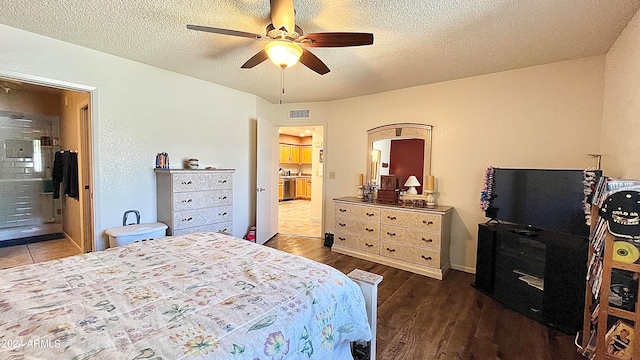 bedroom with ceiling fan, connected bathroom, dark wood-type flooring, and a textured ceiling