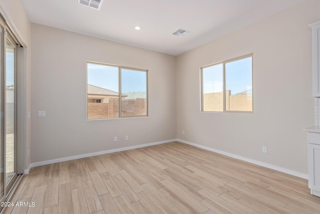 unfurnished room featuring light wood-type flooring, baseboards, and visible vents