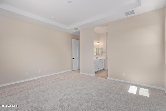 unfurnished bedroom featuring light carpet, ensuite bath, visible vents, and baseboards
