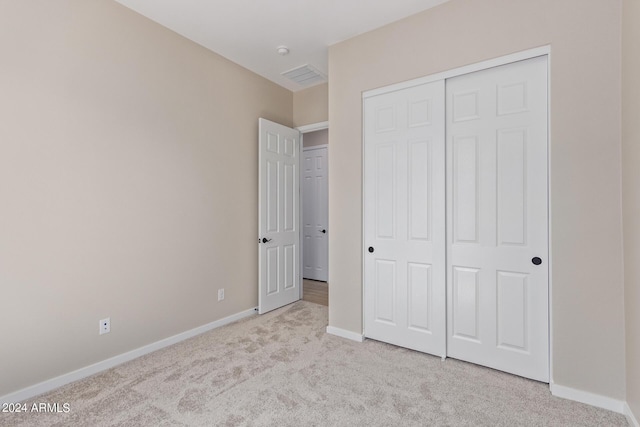 unfurnished bedroom featuring carpet floors, visible vents, baseboards, and a closet