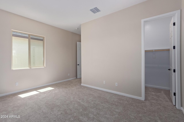 unfurnished room with carpet, visible vents, and baseboards