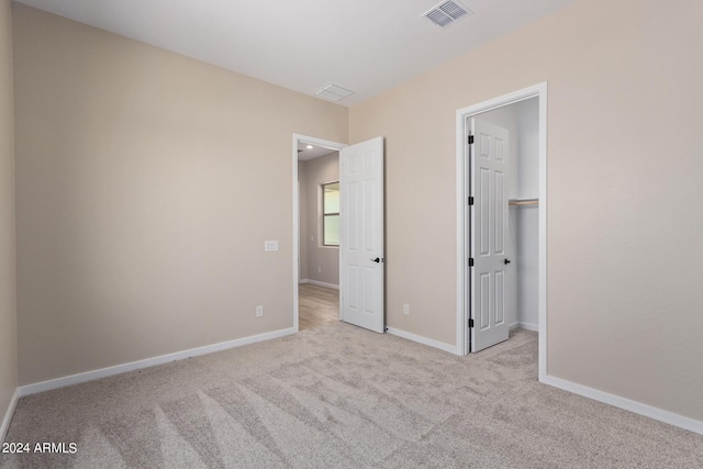 unfurnished bedroom featuring carpet, a walk in closet, visible vents, and baseboards