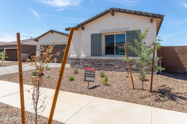 view of front of property featuring a garage, driveway, fence, and stucco siding