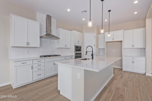 kitchen with visible vents, light wood-style flooring, appliances with stainless steel finishes, wall chimney range hood, and a sink