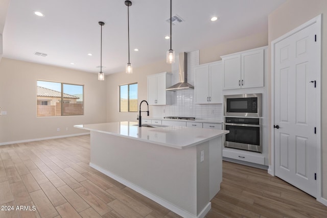 kitchen featuring appliances with stainless steel finishes, visible vents, a sink, and wall chimney exhaust hood