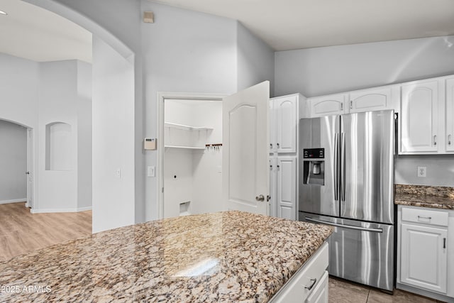 kitchen featuring stainless steel refrigerator with ice dispenser, white cabinets, and dark stone counters